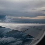 Scenic view from airplane window of wing and clouds at twilight, evoking travel feelings.