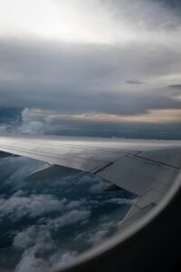 Scenic view from airplane window of wing and clouds at twilight, evoking travel feelings.